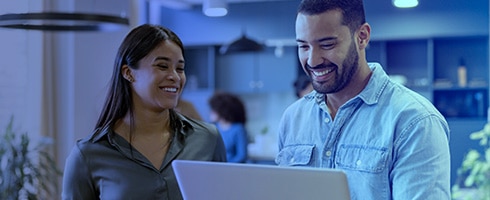 Two smiling coworkers at laptop